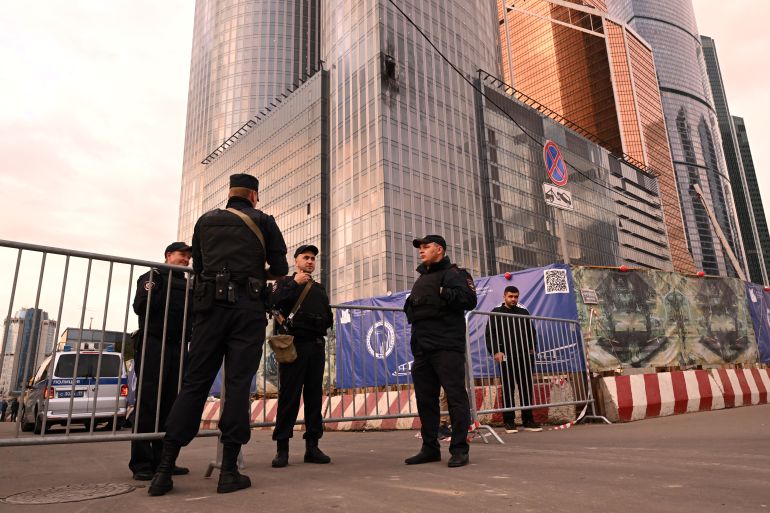 Law enforcement officers stand next to a damaged building of the Moscow International Business Center (Moskva City) following a drone attack in Moscow on August 23, 2023. - A Ukrainian drone attack on Moscow damaged a building in a central business district, authorities said on August 23, in the sixth straight night of aerial attacks on Russia's capital region. (Photo by NATALIA KOLESNIKOVA / AFP)