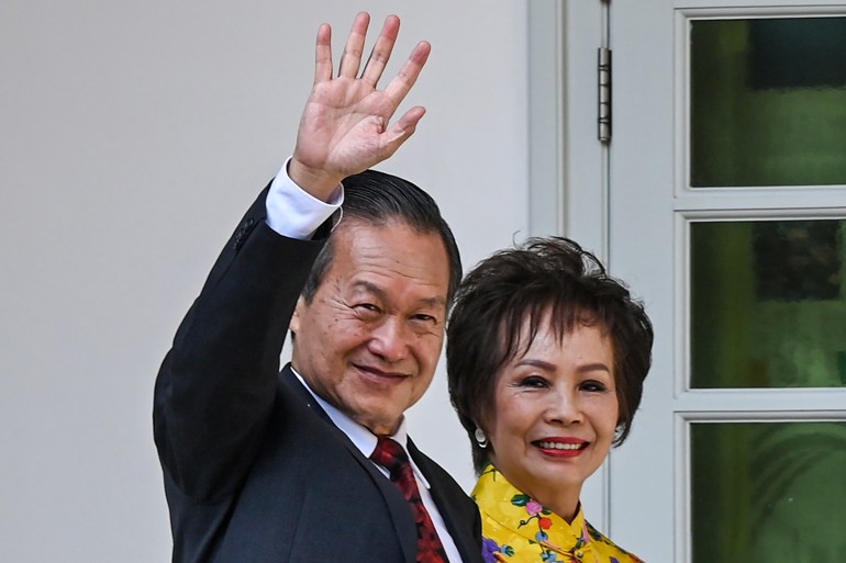 Tan Kin Lian with his wife. He is waving and smiling.