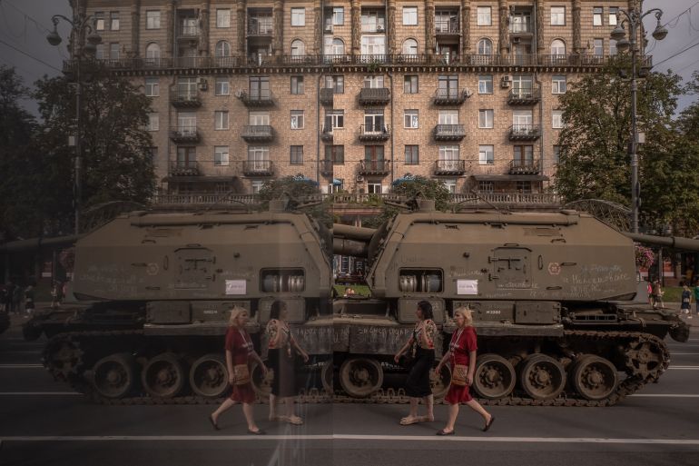 Two women walk past destroyed Russian armoured military vehicles on display in main street Khreshchatyk