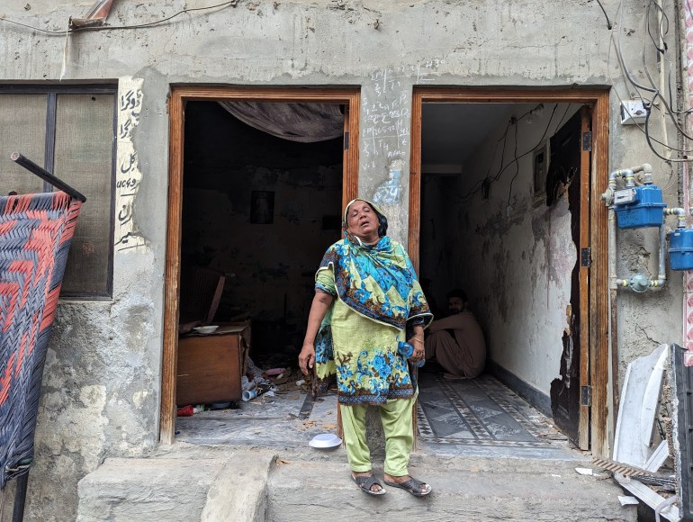 A woman standing outside her destroyed home in Christian Colony