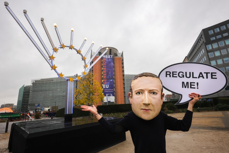 IMAGE DISTRIBUTED FOR AVAAZ - A campaigner from the global citizens movement Avaaz wearing a mask of Facebook CEO Mark Zuckerberg holds a sign reading "Regulate me", outside the European Commission on the day the Digital Services Act is published