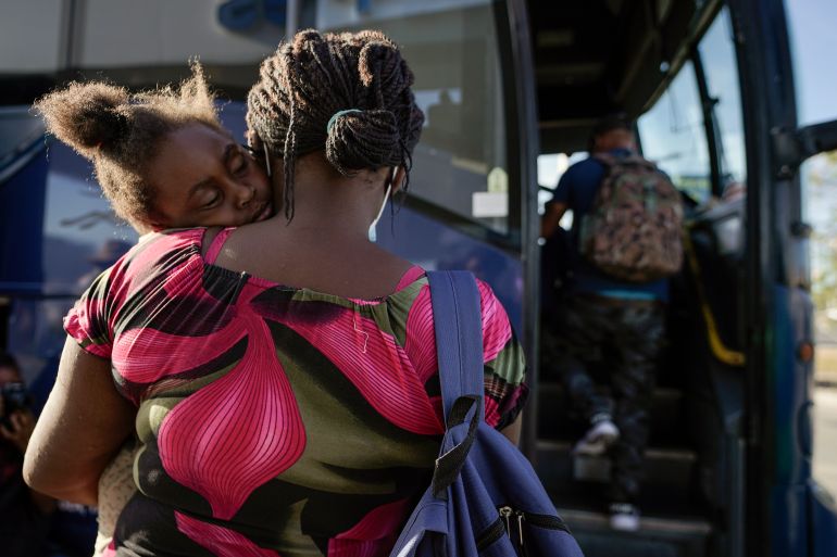 A child sleeps on the shoulder of a woman as they prepare to board a bus to San Antonio moments after a group of migrants, many from Haiti, were released from custody upon crossing the Texas-Mexico border