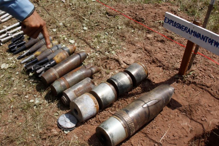 FILE - A Cambodian demining expert points to unexploded bombs displayed on the ground before a destruction ceremony in Preah Vihear province, about 245 kilometers (152 miles) north of Phnom Penh, Cambodia, Thursday, July 7, 2011. Three demining experts from the Cambodian Self Help Demining (CSHD), a non-government demining organization based in Cambodia, were killed Monday, Jan. 10, 2022, while trying to defuse a anti-tank mine in the Chum Chan District, Preah Vihear Province. (AP Photo/Heng Sinith, File)