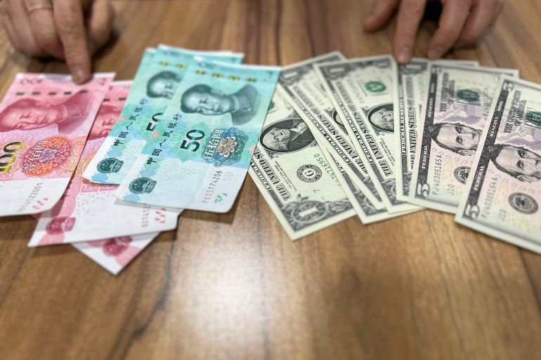 Chinese yuan and US dollar notes, side by side on a table, in Seoul, South Korea, on May 3, 2023