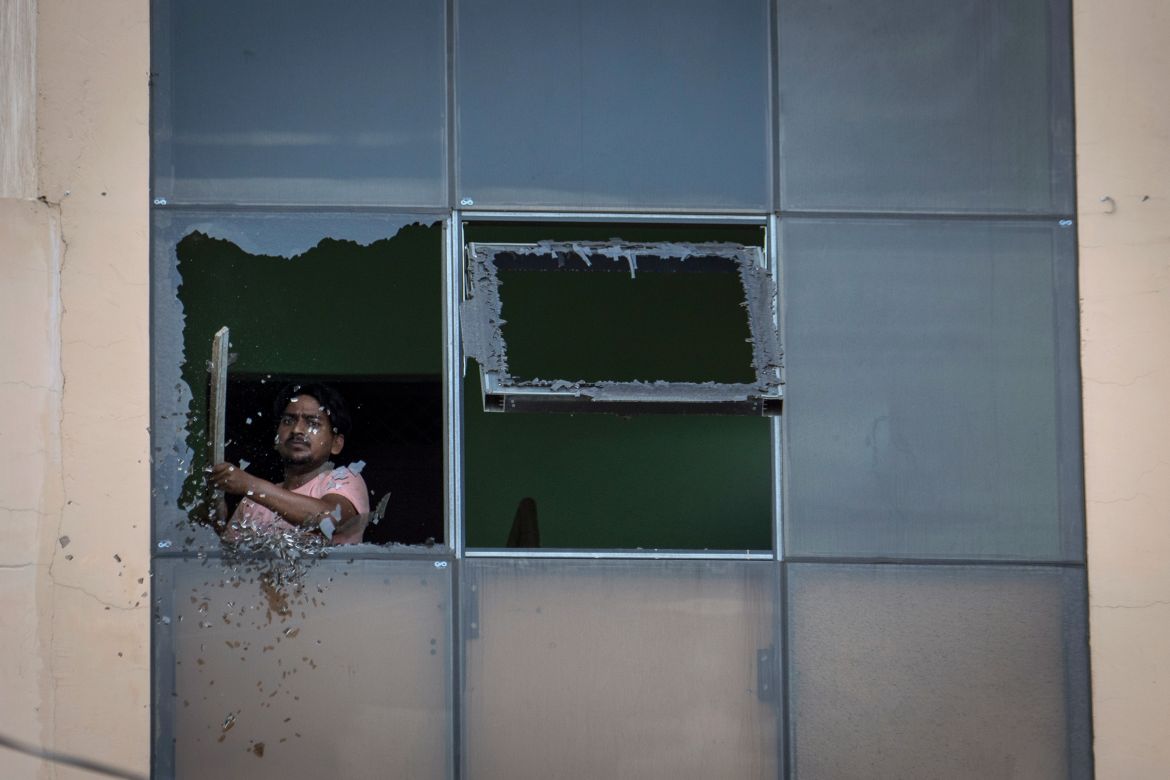 A worker removes broken glass from a window of a restaurant