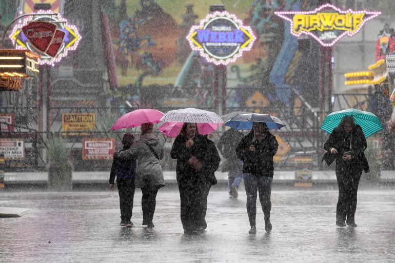 People under umbrellas walk in the rain at the first day of the Cranger Kirmes in Herne, Germany