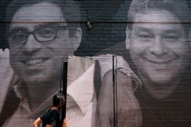 A person walks by mural showing Siamak Namazi
