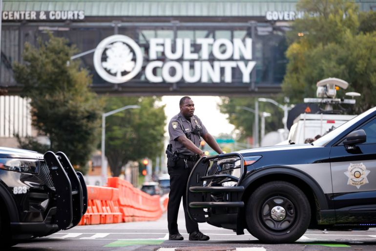 A sheriff's deputy stands guard near the Fulton County Courthouse, Monday, Aug. 14, 2023, in Atlanta. Authorities in Georgia said Thursday they're investigating threats targeting members of the grand jury that indicted former President Donald Trump and 18 of his allies. (AP Photo/Alex Slitz)