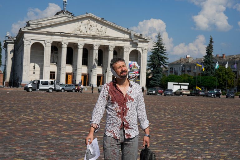 An injured man walks in Krasna square with the Taras Shevchenko Chernihiv Regional Academic Music and Drama Theatre in the background, after a Russian attack, in Chernihiv, Ukraine