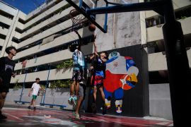 People play basketball in front of a wall painted with JIP, the FIBA Basketball World Cup mascot, Thursday, Aug. 17, 2023, in Taguig city Philippines