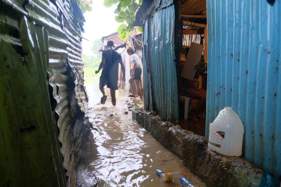People walk between flooded houses in the Dominican Republic after Tropical Storm Franklin dumped heavy rains