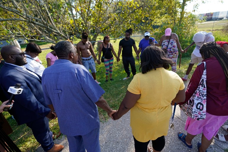 Black residents standing a circle holding hands in prayer following the Florida shooting