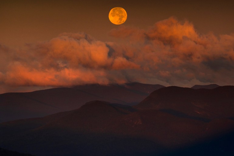 The blue supermoon sets over the White Mountain National Forest at sunrise
