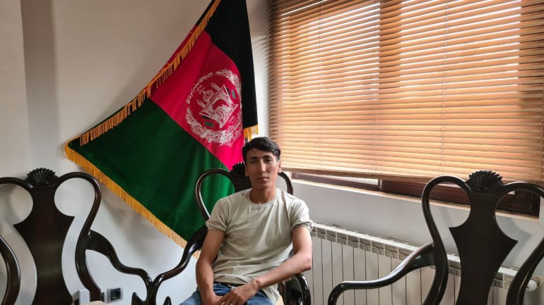 Saber Assadi in front of an Afghanistan flag