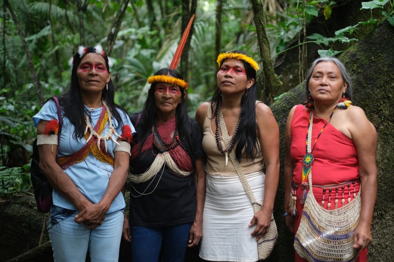 Four Indigenous women stand together in the Ecuadorian Amazon.