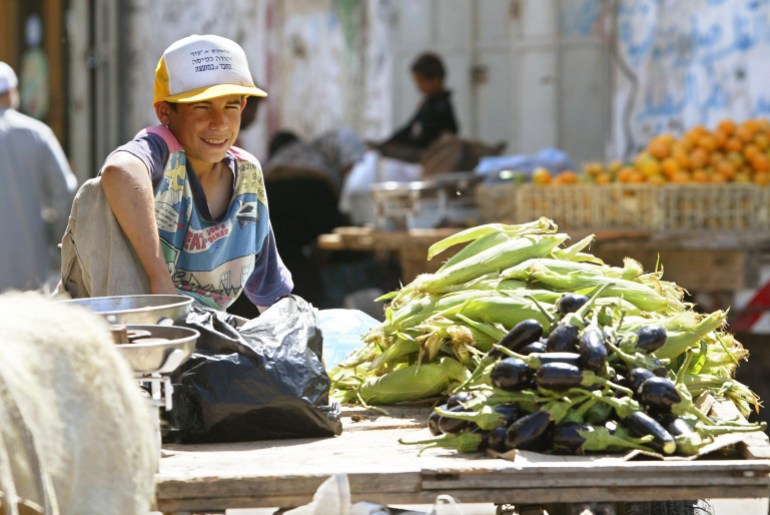 A Palestinian boy sells corn and aubergines
