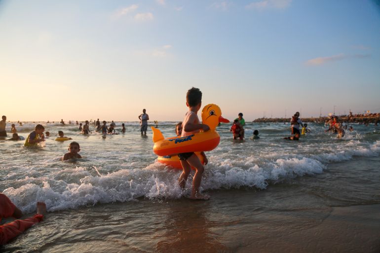 A child in a duck floatie runs from a small wave