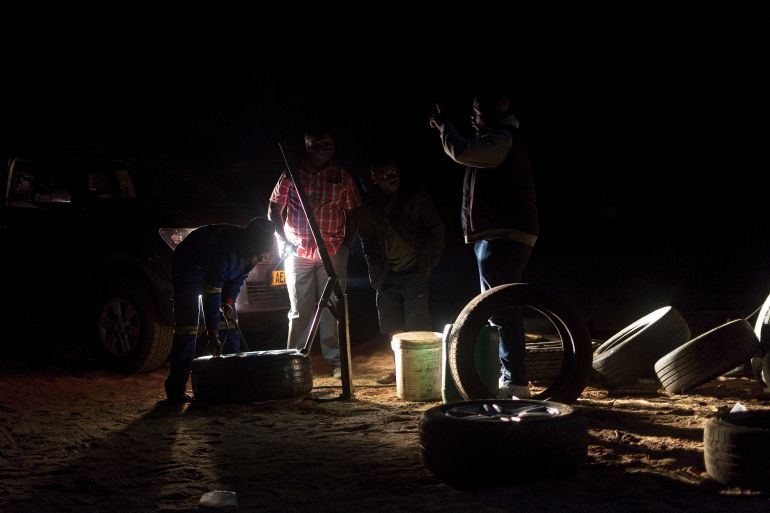 Young men fix a tyre in the dark at an all-night truck stop in Insuza along the highway to Hwange Thermal Power Station, Zimbabwe