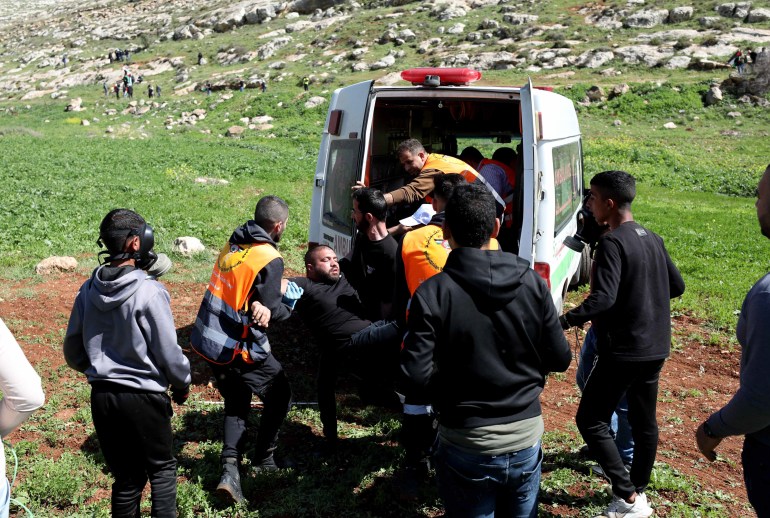 Des travailleurs et des bénévoles des services médicaux d'urgence chargent un homme blessé dans une ambulance sur le lieu des manifestations