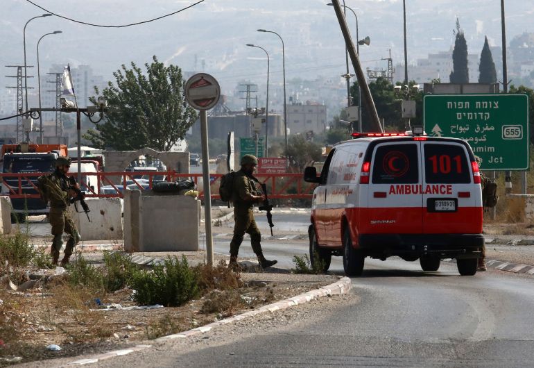 Israeli soldiers stop an ambulance at a checkpoint