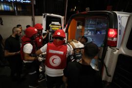 Palestinian Red Cresecent workers loading a man into an ambulance