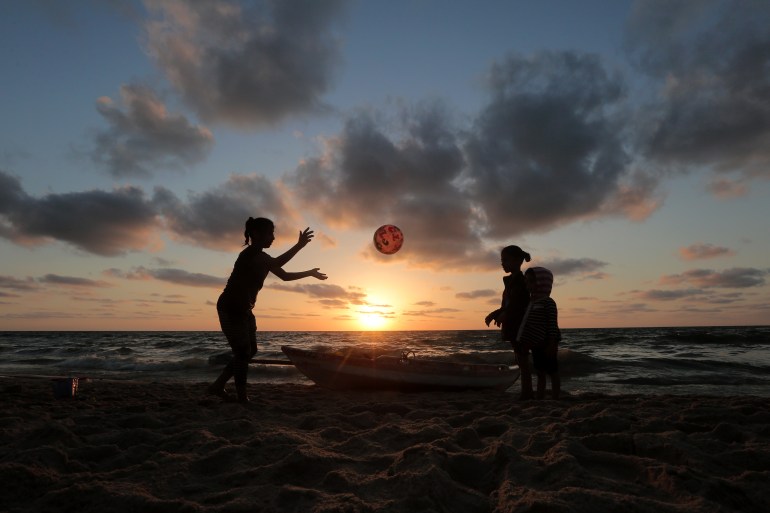 孩子们在夕阳下在沙滩上打球