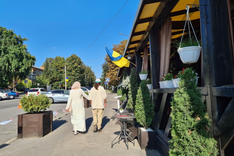 Um casal de peregrinos caminhando sob uma bandeira ucraniana no centro de Uman