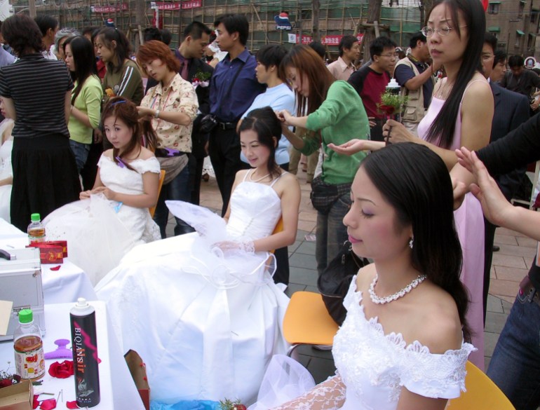 Chinese brides prepare for a mass wedding for some 50 couples called "Rose Wedding" in Shanghai October 5, 2003 coinciding with the week-long National Day holiday festivities. More couples are getting married after a new law took effect last October, wherein couples no longer need to get a letter from their employers to testify they are still single and the premarital health test in no longer required. Picture taken October 5, 2003. REUTERS/Stringer CC/CP