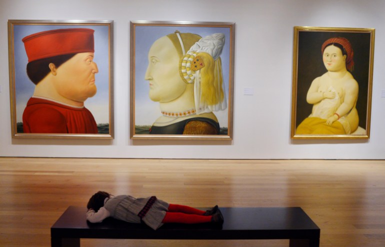 A child looks at paintings by Fernando Botero