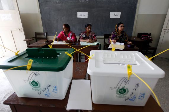Election officials wait for voters inside a polling station during a re-polling for the general elections in Karachi.