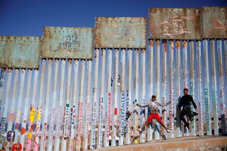 Cristian Joel Morales (L) and Victor David Reyes Madrid, migrants from Honduras, part of a caravan of thousands traveling from Central America en route to the United States, pose in front of the border wall between the U.S. and Mexico in Tijuana, Mexico, November 23, 2018. REUTERS/Kim Kyung-Hoon SEARCH "KYUNG-HOON DREAMS" FOR THIS STORY. SEARCH "WIDER IMAGE" FOR ALL STORIES. TPX IMAGES OF THE DAY
