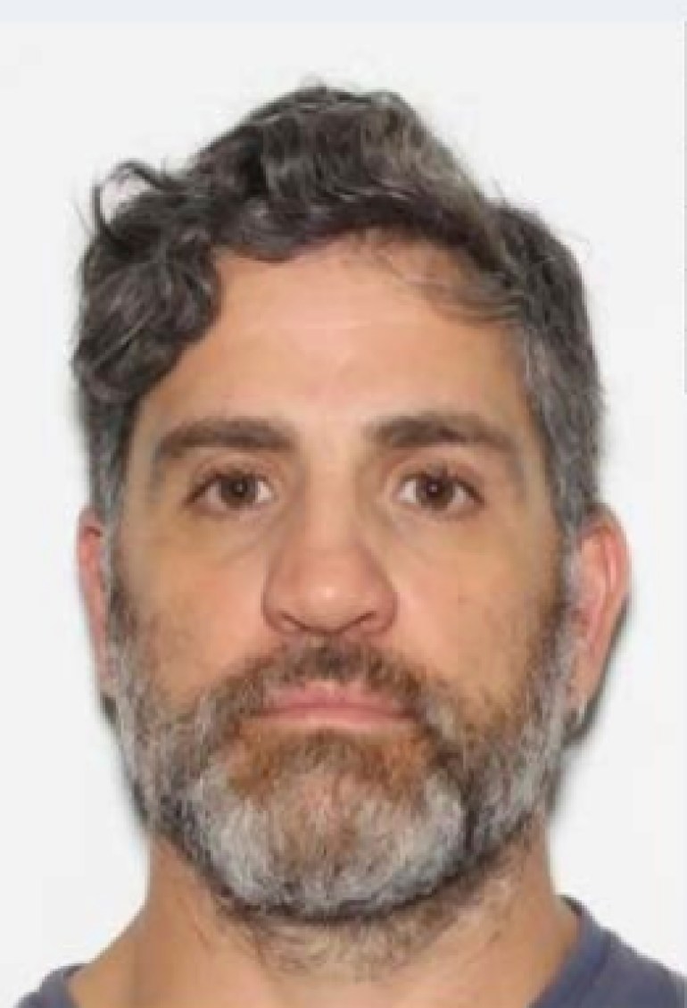 Una foto segnaletica di Domenico Pezzola, un uomo bianco con una barba grigia trasandata.
