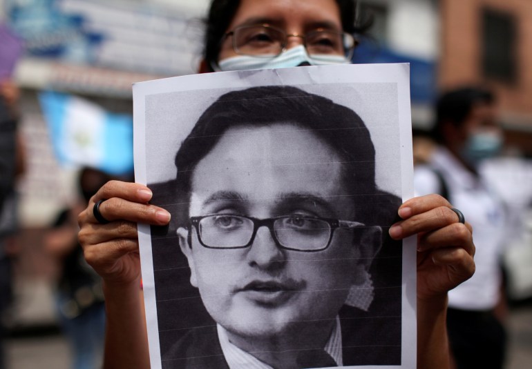 A woman holds a picture of Juan Francisco Sandoval, who was removed by Guatemala's Attorney General as head of the Special Prosecutor's Office Against Impunity (FECI) during a protest in Guatemala City, Guatemala July 24, 2021. The picture is a large black-and-white print-out.