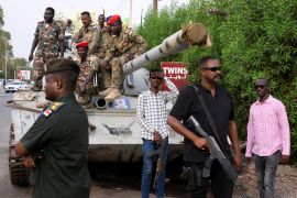 Members of military armed guard and members in plainclothes are seen around a tank after the arrival of Sudan's General Abdel Fattah al-Burhan