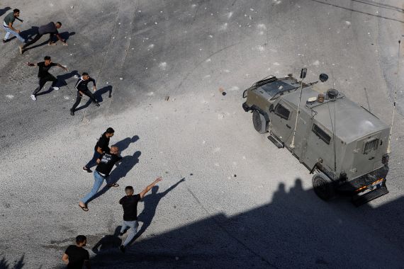 Palestinians throw objects next to an Israeli military vehicle during a raid near Tubas in the Israeli-occupied West Bank