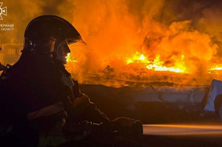 A firefighter working at scene of a drone attack in Odesa region He is silhouetted against the orange flames and smoke