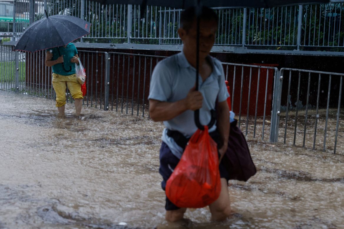 People make their way through a flooded area after heavy rains