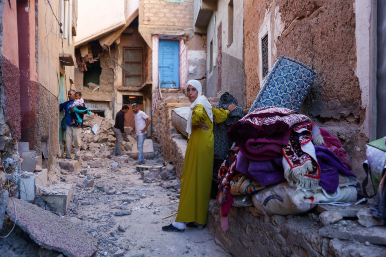 A woman looks on as people inspect damaged buildings, in the aftermath of a deadly earthquake in Moulay Brahim, Morocco, September 10, 2023. REUTERS/Hannah McKay