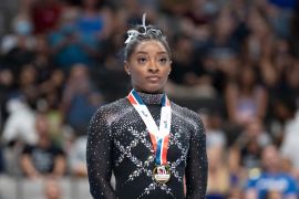 Gymnast Simone Biles stands wearing a gold medal round neck