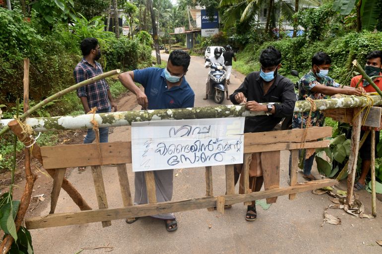 Residents fix a sign reading "Nipah containment zone" on a barricade, put up to block a road after the authorities declared the area a containment zone, to prevent the spread of Nipah virus in Ayanchery village in Kozhikode district, Kerala, India, September 13, 2023. REUTERS/Stringer NO RESALES. NO ARCHIVES