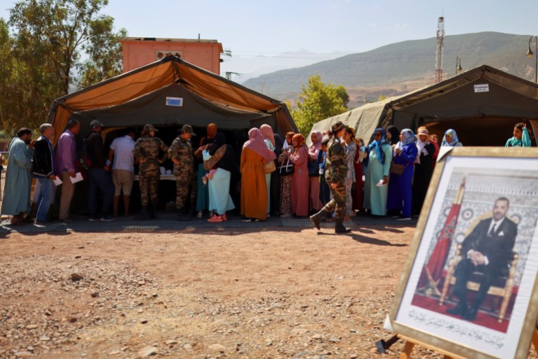 Un'immagine del re Mohammed del Marocco viene vista mentre i sopravvissuti al terremoto fanno la fila in un ospedale militare da campo