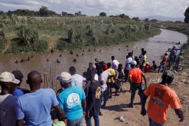 Haitians gather near the Massacre River, which forms part of the border between their country and the Dominican Republic, as farmers and rural workers nearby construct a canal [File: Octavio Jones/Reuters]