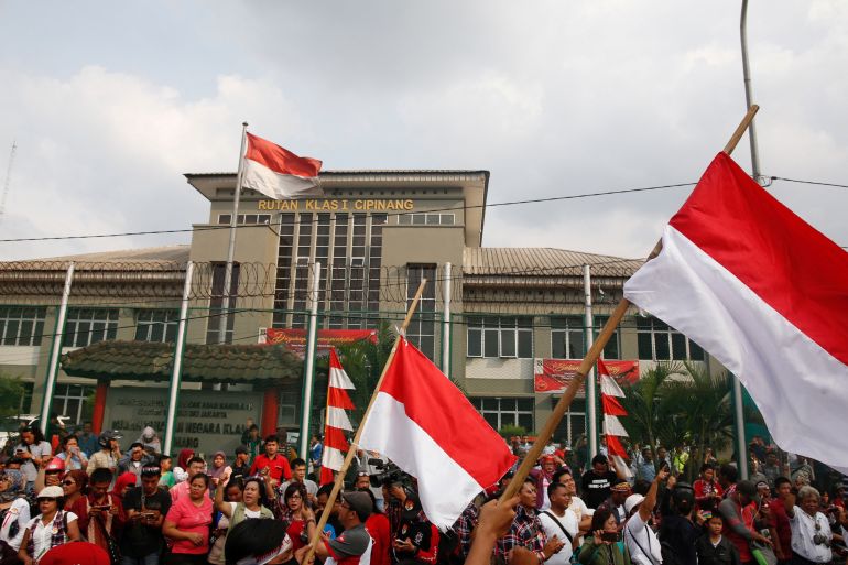 A crowd of people outside the Cipinang prison in Indonesia. They are supporters of former Jakarta governor Basuki Tjahaja Purnama. They are holding Indonesian flags
