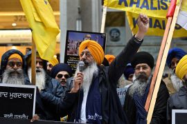 A demonstrator uses a microphone as others hold flags and signs as they protest outside India's consulate, a week after Canada's Prime Minister Justin Trudeau raised the prospect of New Delhi's involvement in the murder of Sikh separatist leader Hardeep Singh Nijjar, in Vancouver, British Columbia, Canada September 25, 2023. REUTERS/Jennifer Gauthier