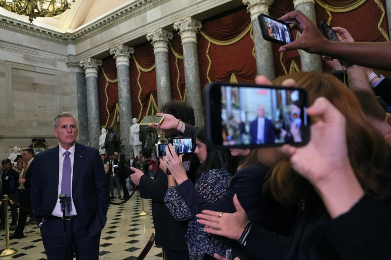 Reporters hold up cellphones and other equipment to record as House Speaker Kevin McCarthy takes questions on the black-and-white checkered floor of the Capitol