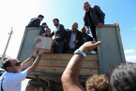 Refugees from Nagorno-Karabakh region receive aid as they ride in the back of a truck upon their arrival in the border village of Kornidzor, Armenia [Irakli Gedenidze/Reuters]