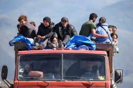 Refugees from the Nagorno-Karabakh region ride in a truck upon their arrival at the border village of Kornidzor, Armenia, September 27, 2023 [Irakli Gedenidze/Reuters]
