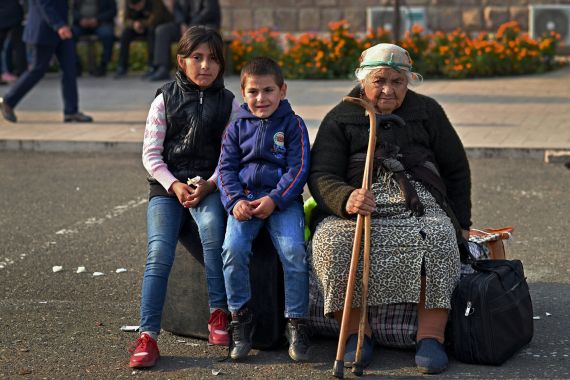 An elderly woman and children sit on bags of belongings as residents gather in central Stepanakert to leave Nagorno-Karabakh, a region inhabited by ethnic Armenians,