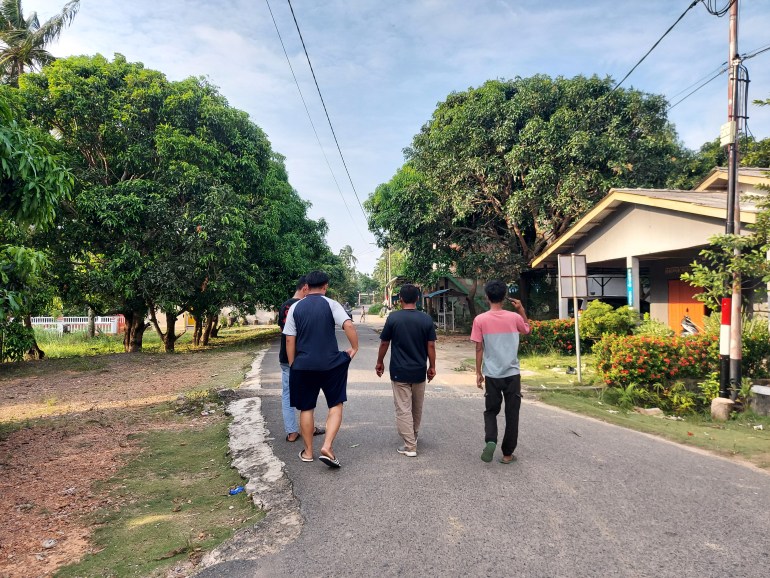 Young men walking down a tree-lined street in Sembulang. It looks like a peaceful place. They are walking away from the camera.
