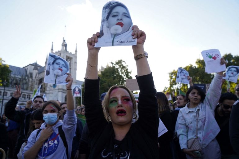 People chant slogans and hold the pictures of Mahsa Amini during a demonstration in central London on October 8, 2022. Amini, 22, died on September 16, three days after falling into a coma following her arrest by Iran's morality police for allegedly breaching the Islamic republic's strict dress code for women.